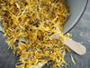 Nahaufnahme von getrockneten Calendula-Blüten auf einem Löffel, perfekt für die Zubereitung eines natürlichen Kräutertees.