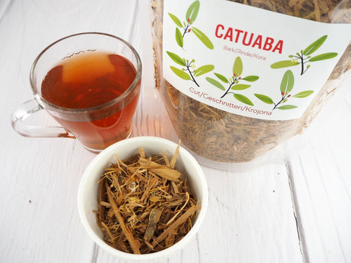 Getrocknete Catuaba-Rinde neben gebrauten Catuaba- und Planta Vera-Markenverpackungen auf hellem Hintergrund.