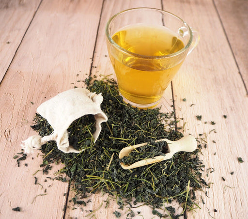 Lose Jiaogulan-Teeblätter neben einer Tasse aufgebrühten Tees, präsentiert von Planta Vera für Qualität und Tradition.