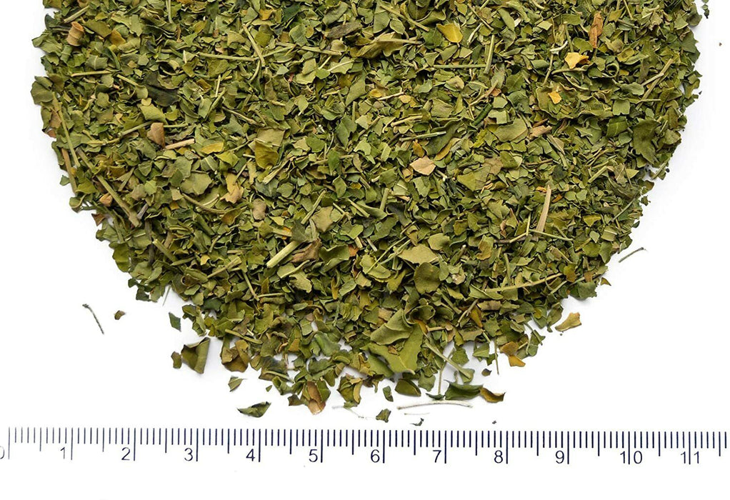 Haufen von getrockneten Moringablättern neben einem Lineal zur Größenangabe, natürliche Superfood-Zutat