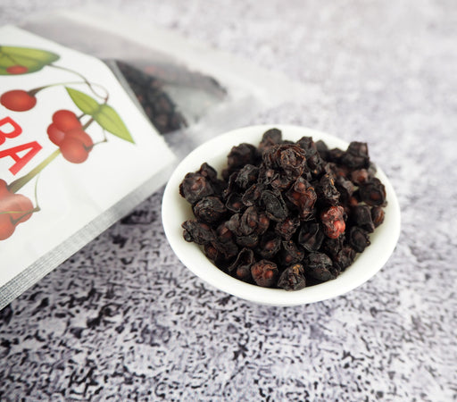 Schisandra-Beeren in einer transparenten Packung neben einer Tasse Tee, auf einem rustikalen Hintergrund, hervorhebung der natürlichen Antioxidantien.