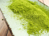 Grünes, gemahlenes Steviablatt auf einer hellen Holzoberfläche, ideal für kalorienfreies Süßen.