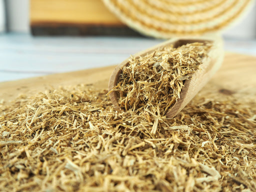 Getrocknete Kräutertee-Zutaten auf einem Holzlöffel, hochwertige lose Blätter für einen gesunden Tee.